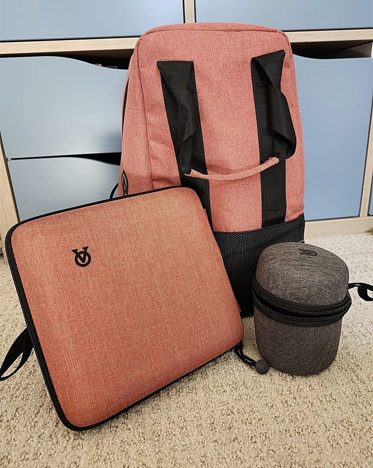 Two coral-coloured Aged & Ore carriers and a small grey zippered case