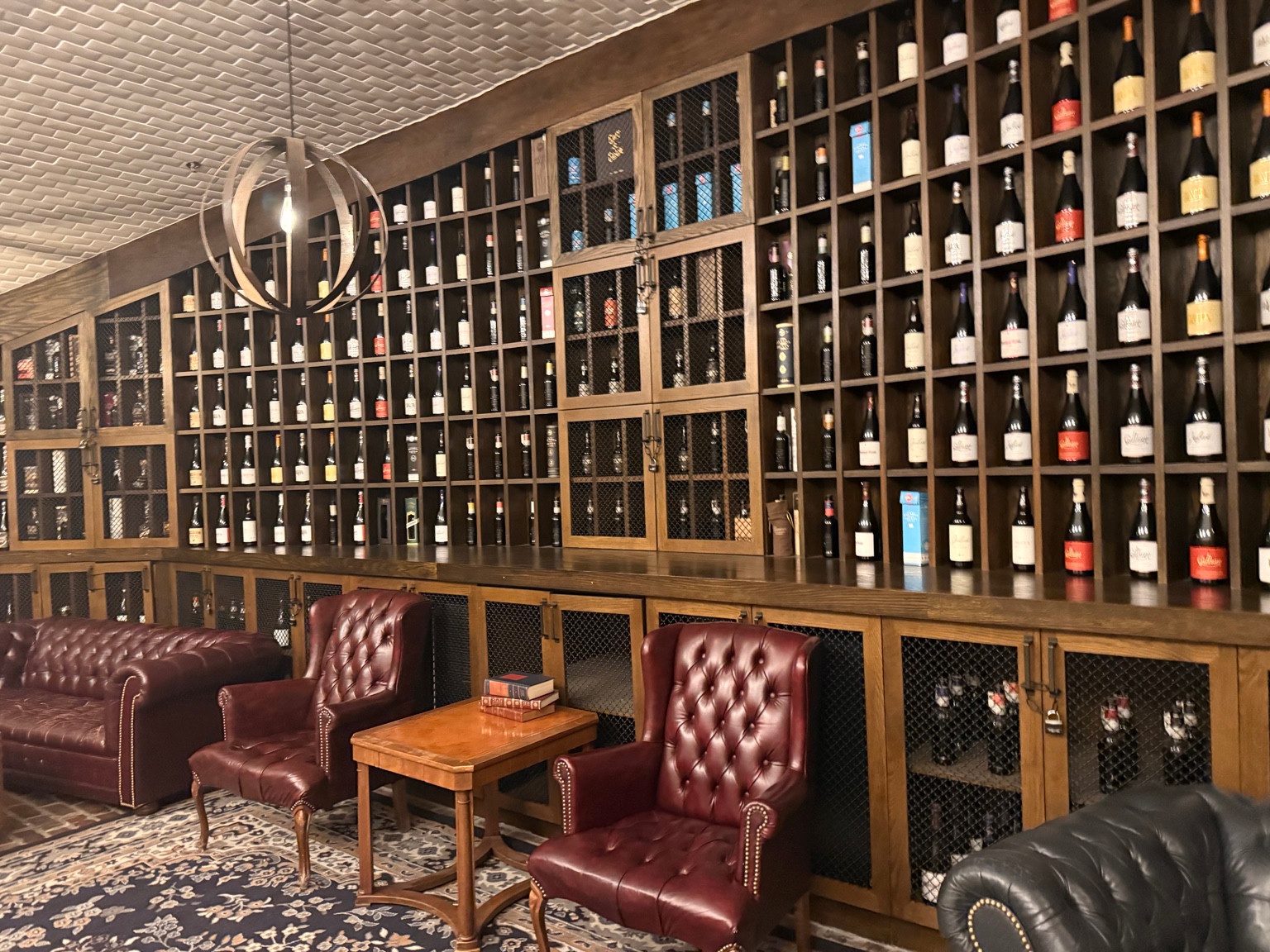 Bottle-filled wooden shelving behind tufted leather chairs and a sofa in the Goose Island Barrel House lounge.